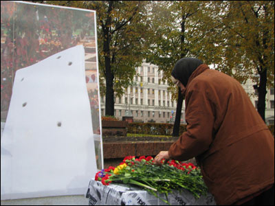 Участница митинга возлагает цветы к фотографии памятника Анне Политковской на Троекуровском кладбище. Фото Веры Васильевой, HRO.org